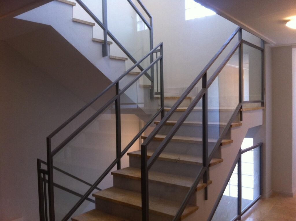 Escalera interior moderna con barandilla metálica y peldaños de madera.